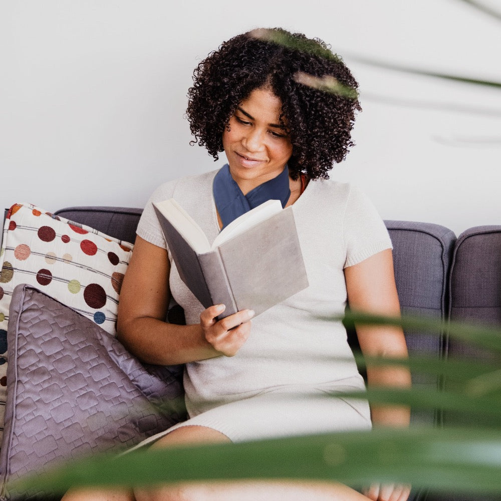 Lady wearing neck warmer while reading a book